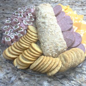 pimento cheese ball or cheese log on a glass serving tray with crackers and meats