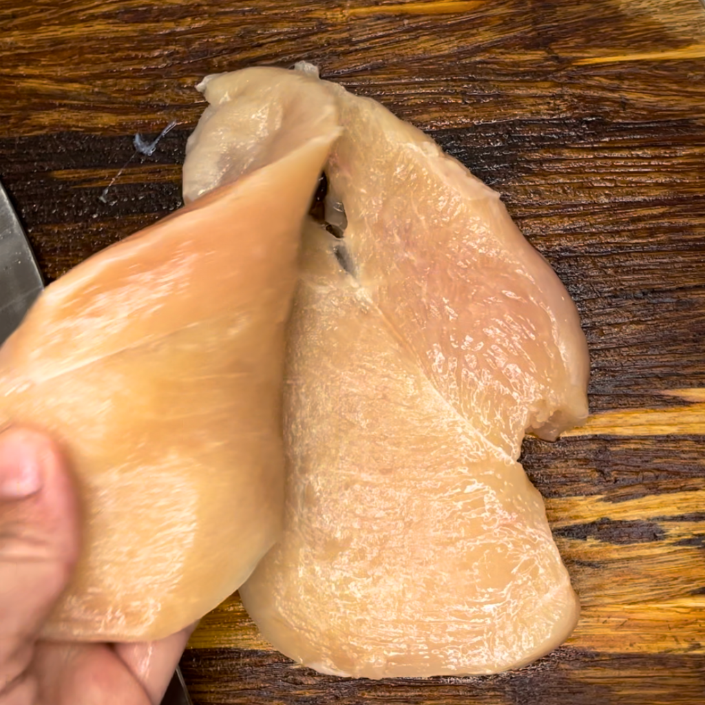 slicing the chicken breast horizontally through the middle of the chicken breasts.