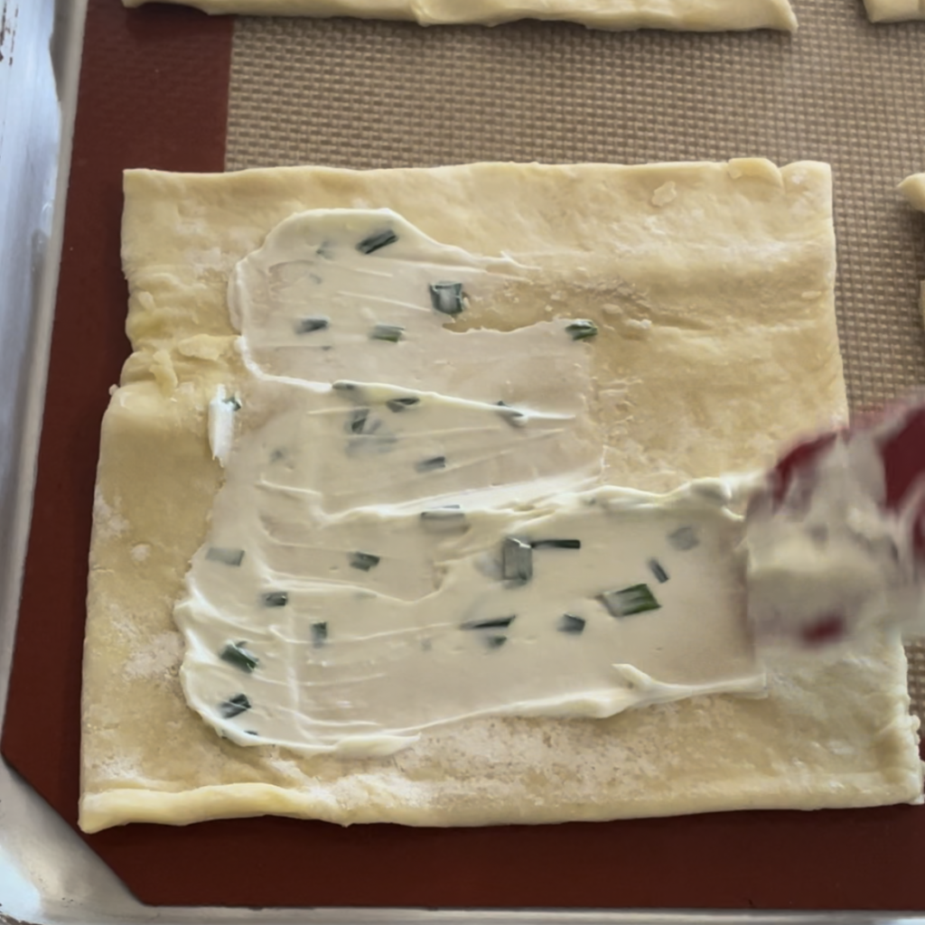 Spreading the cream cheese and chives on the puff pastry