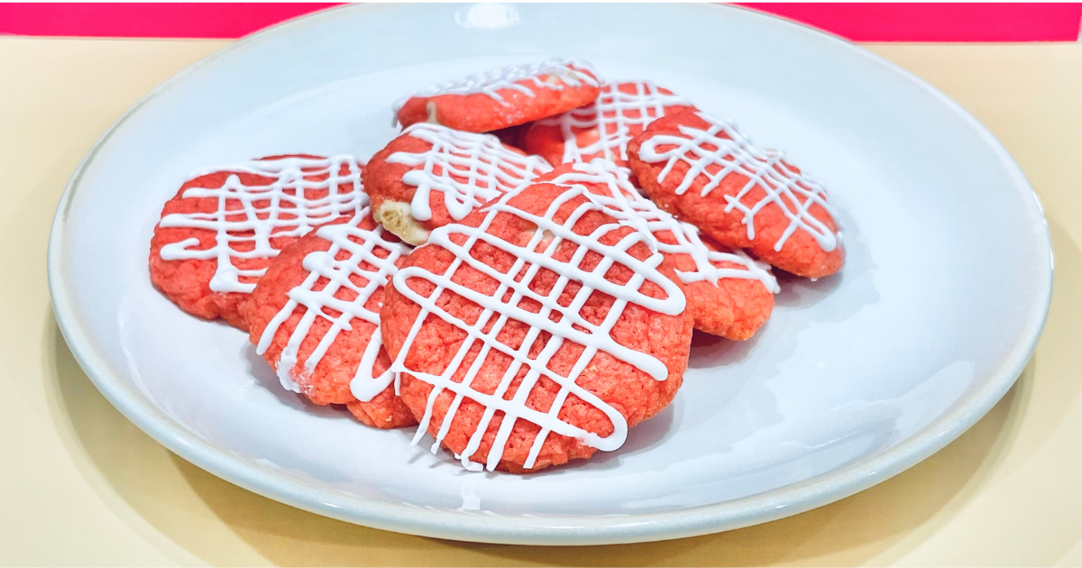 pile of straberry cake box cookies on a white plate drizzled with white chocolate