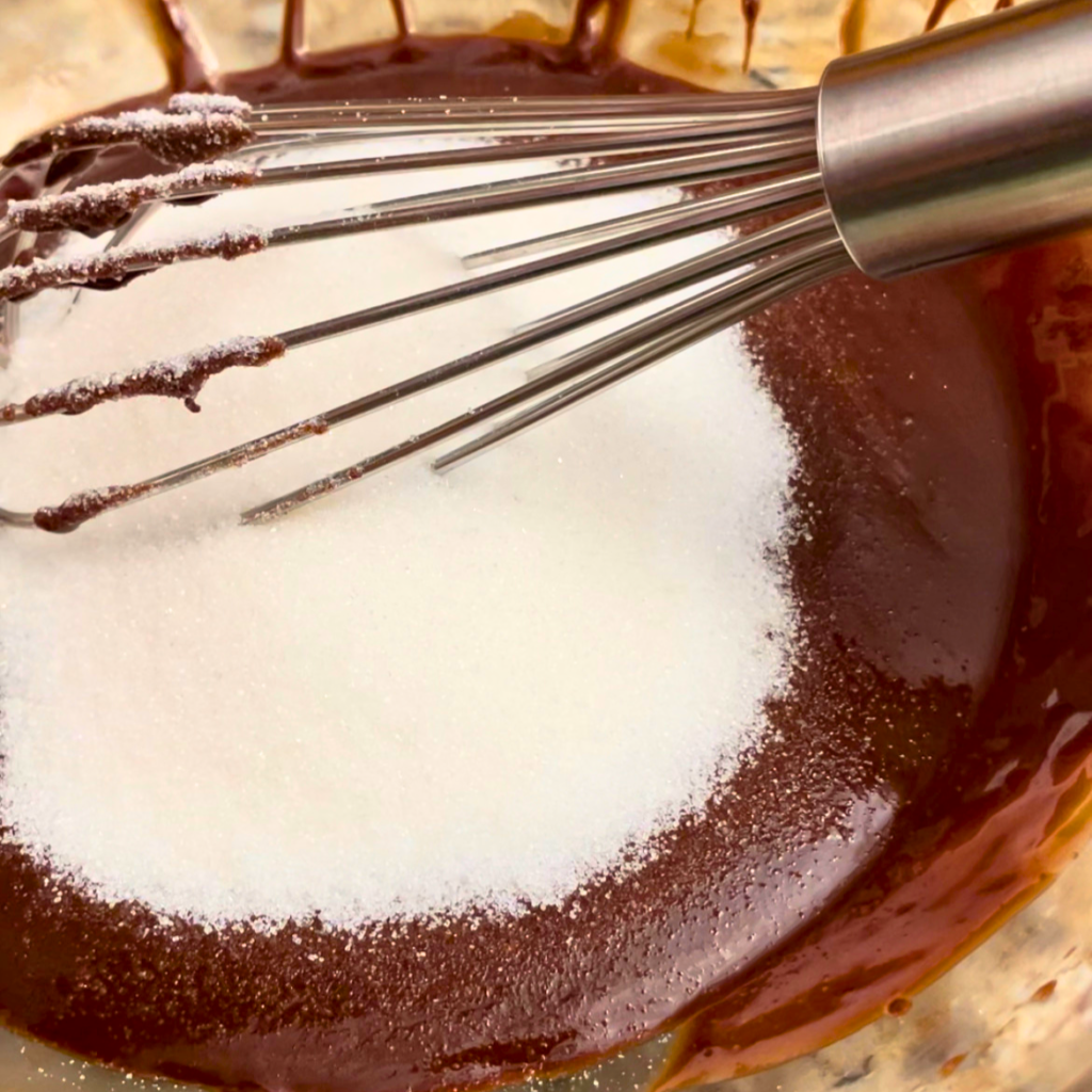 whisking the sugar into the melted chocolate mix in a glass bowl. 