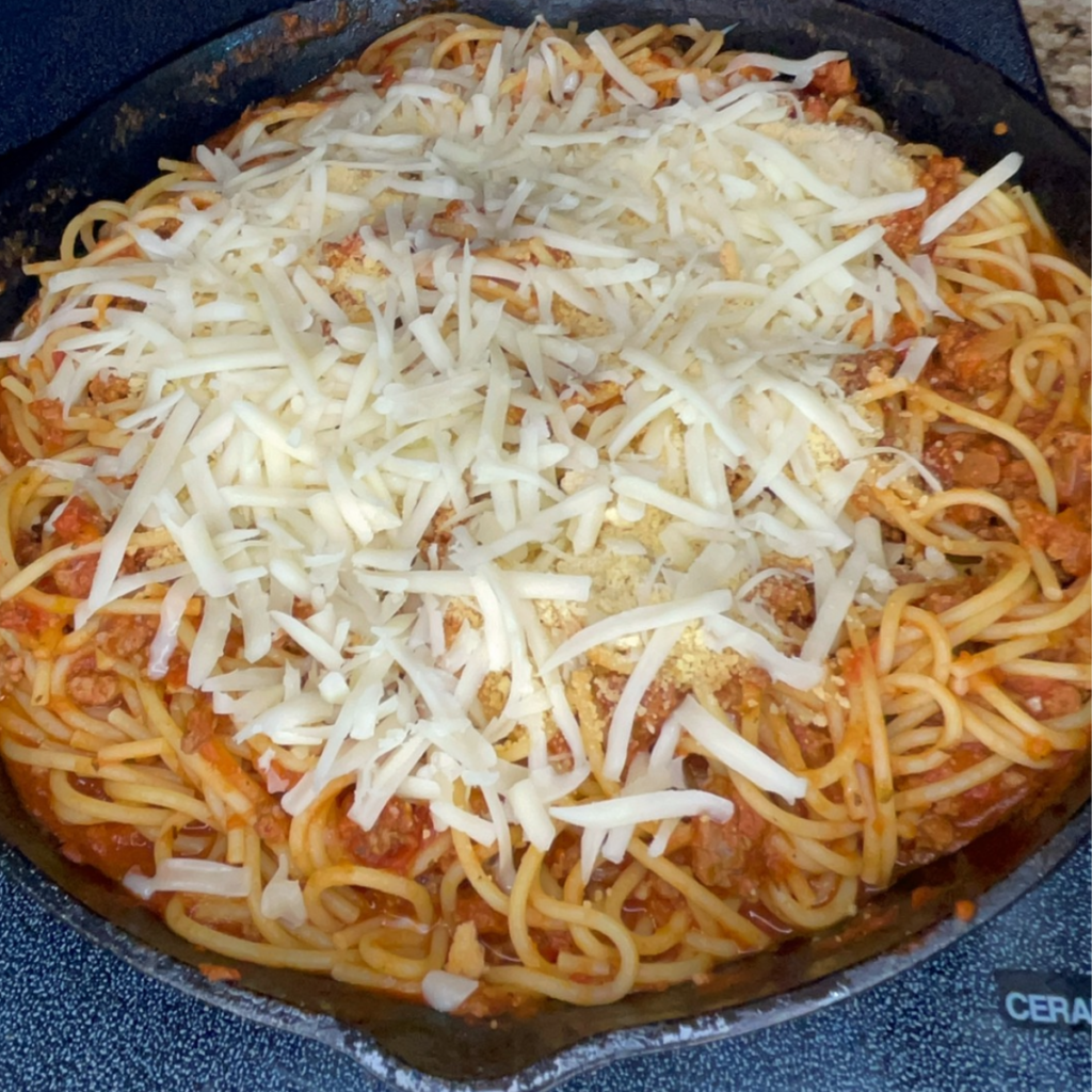 Adding the cheeses to the top of the spaghetti