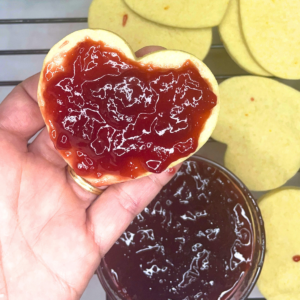 Raspberry jam spread on top of a solid heart cookie