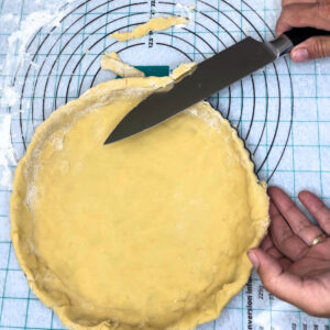 cutting the excess dough off the tart before baking the crust.